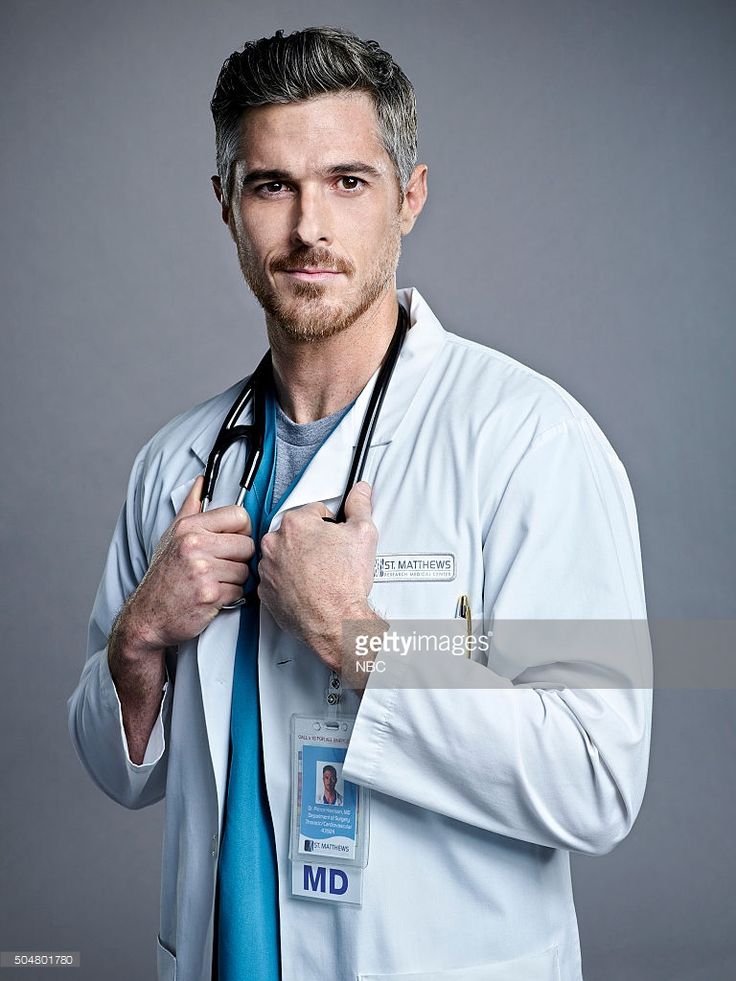 a male doctor in a white coat and blue tie is posing for the camera with his stethoscope