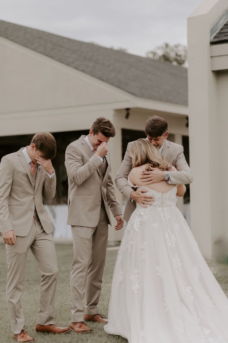 three people standing in front of a building with one woman hugging the other man's chest