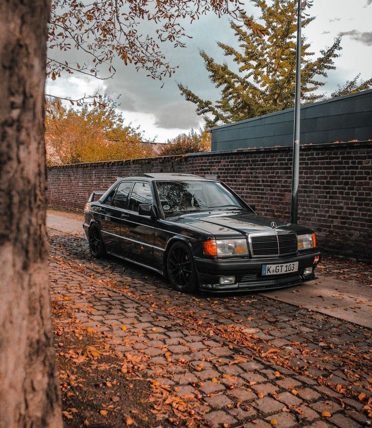 a black car parked in front of a brick building on a cobblestone road