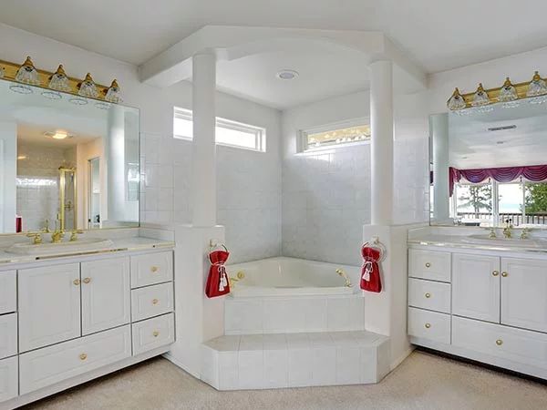 a large bathroom with two sinks and a tub in the middle, along with white cabinets