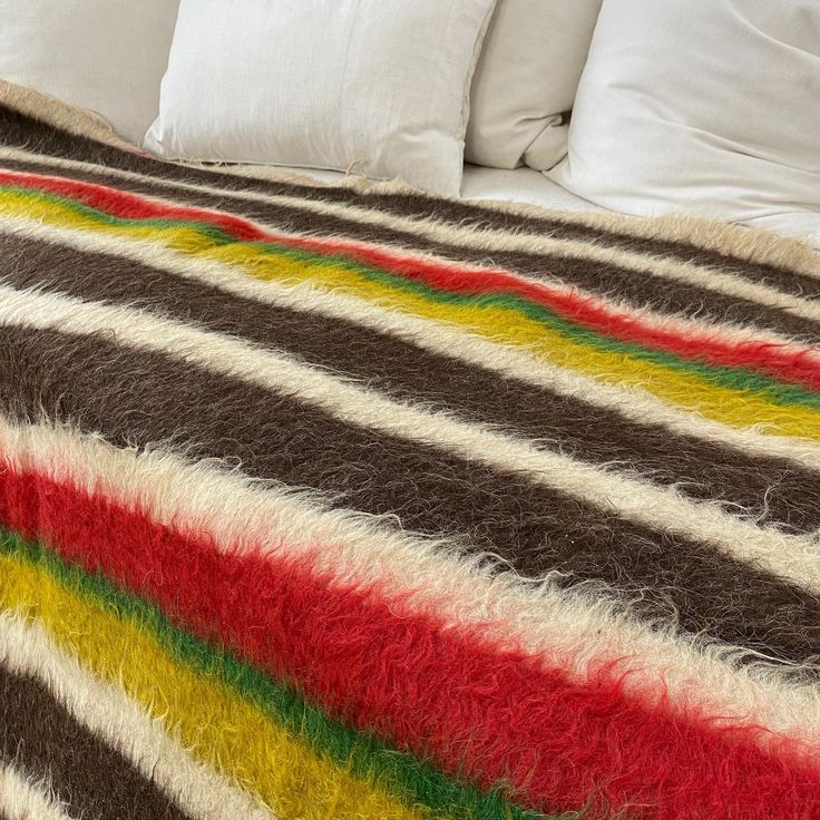 a bed covered in a colorful blanket and pillows