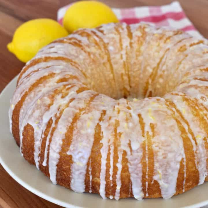 a bundt cake on a plate with lemons in the background