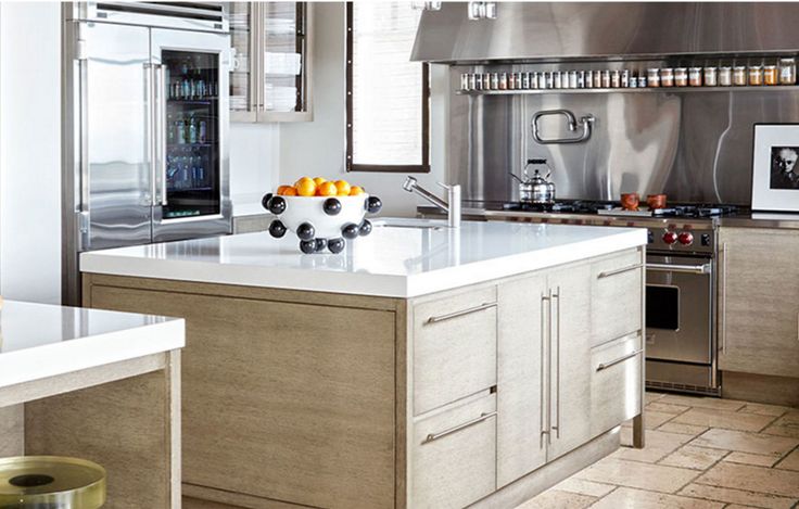 a modern kitchen with stainless steel appliances and white counter tops, along with an island in the middle