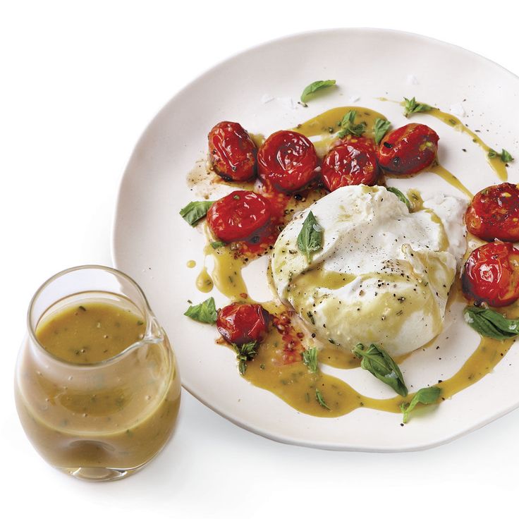 a white plate topped with eggs and tomatoes next to a glass of orange juice on a table