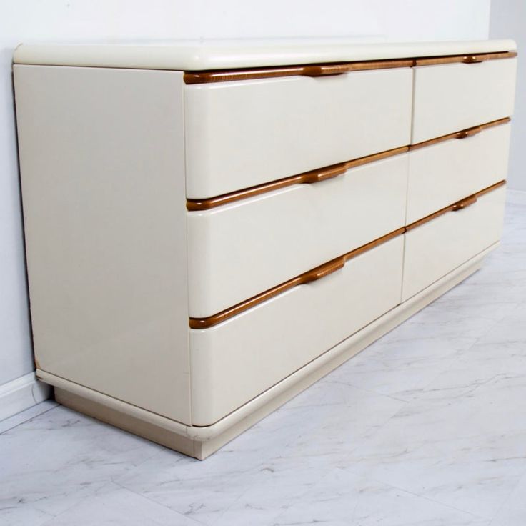 a white dresser with gold handles in a room