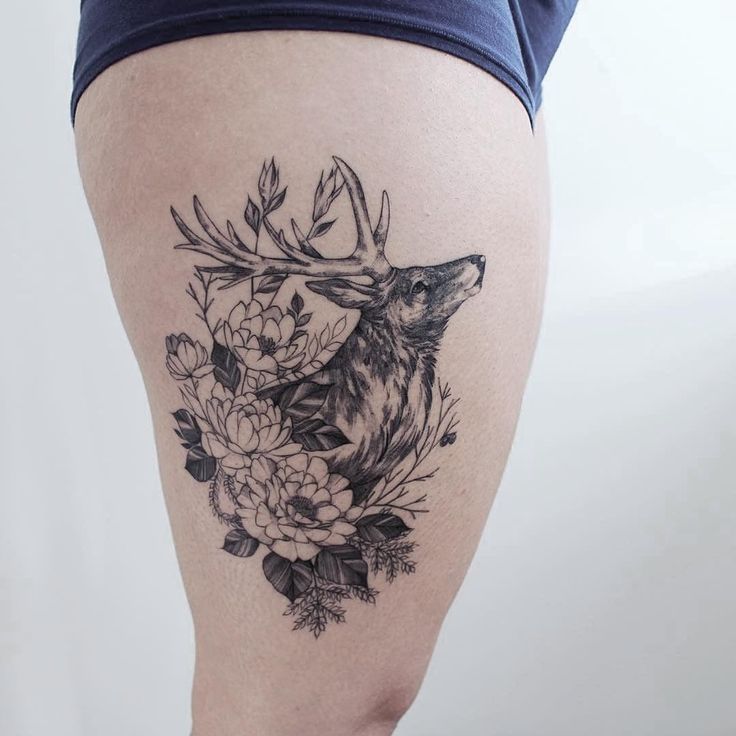 a woman's thigh with a deer and flowers tattoo on it