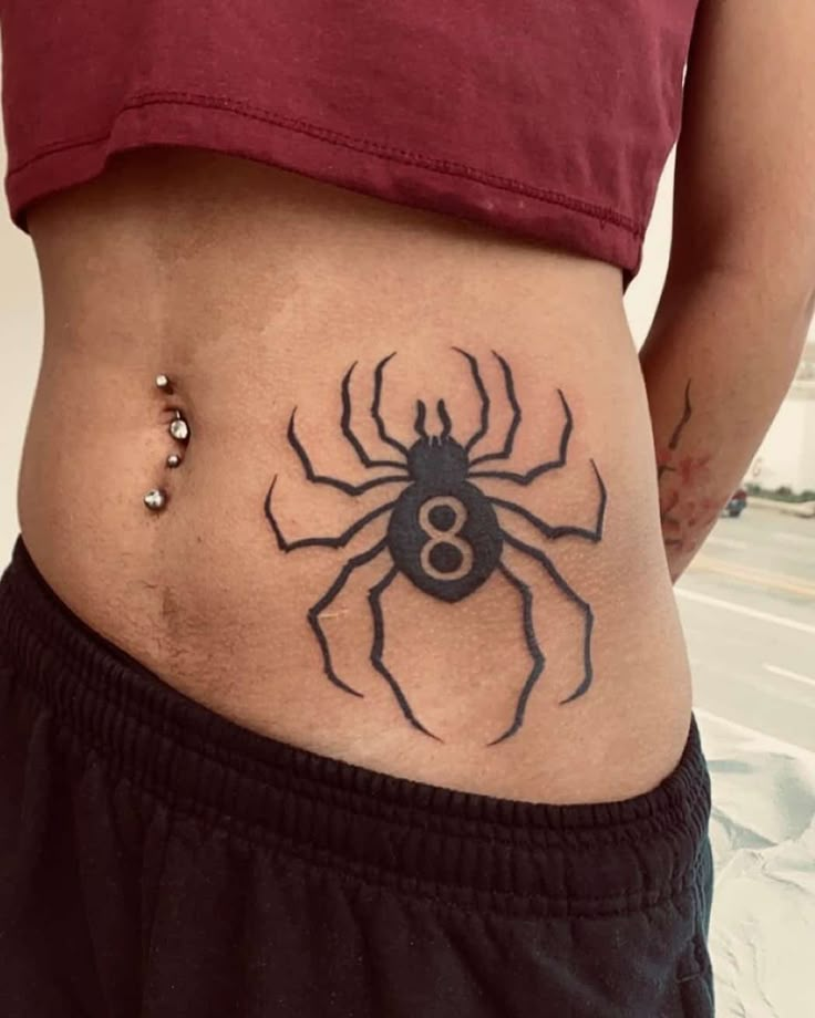 a woman's stomach with a spider tattoo on her belly and the number eight