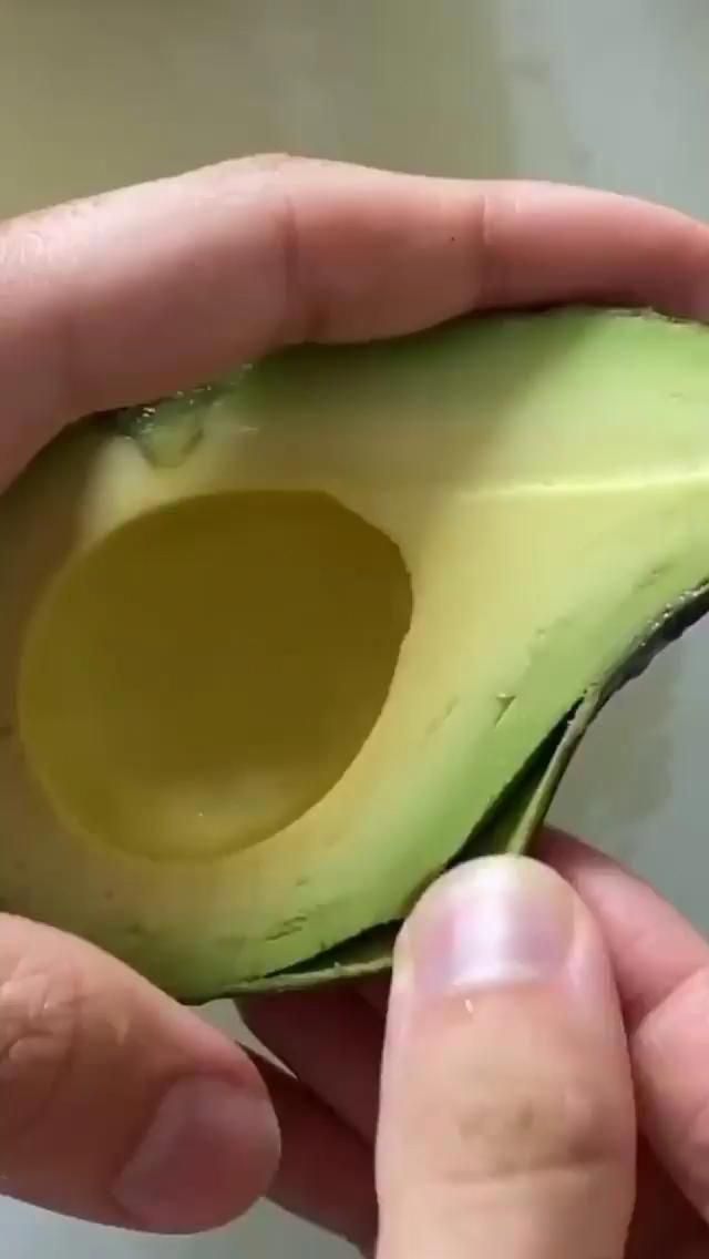 someone is peeling an avocado in half