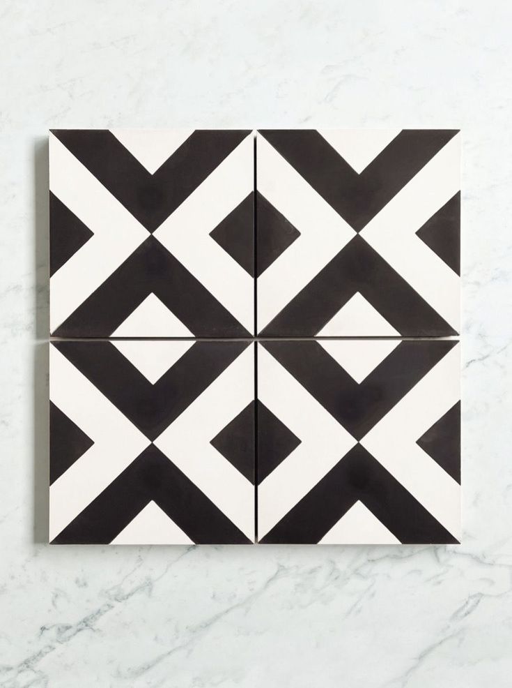 four black and white tiles on a marble countertop, each with an interesting geometric design