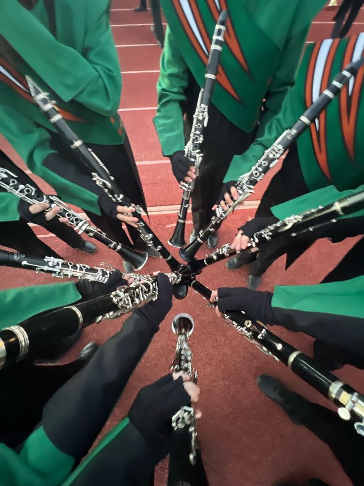 a group of young men in green uniforms holding their hands together and playing the bagpipes