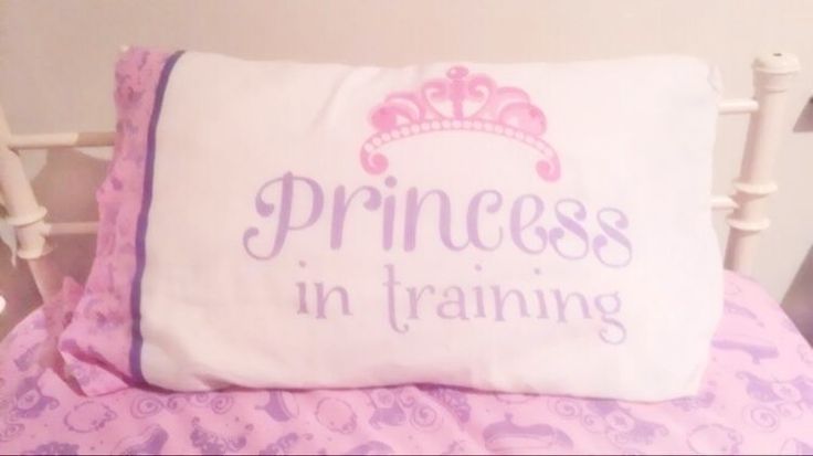 a pillow that says princess in training on the back of a bed with pink and purple bedspread