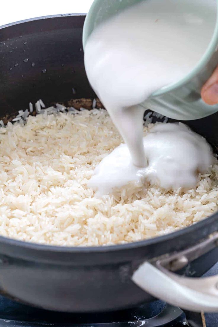 someone is pouring milk over rice in a pan