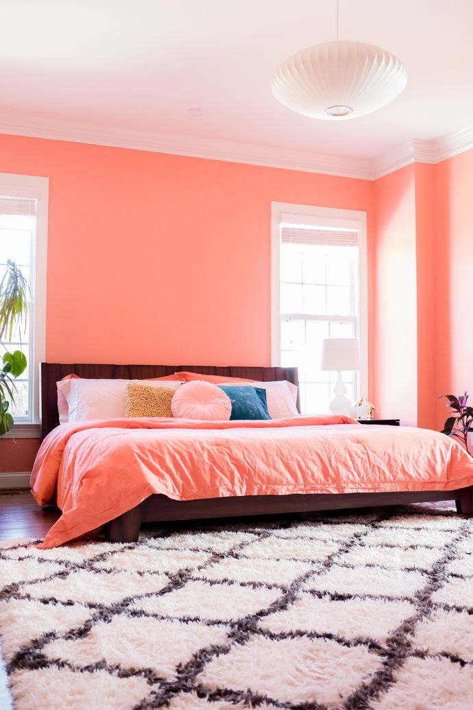 a bedroom with pink walls and white rugs on the floor next to a bed