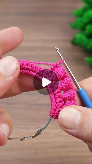 someone is crocheting the end of a piece of pink yarn with a needle