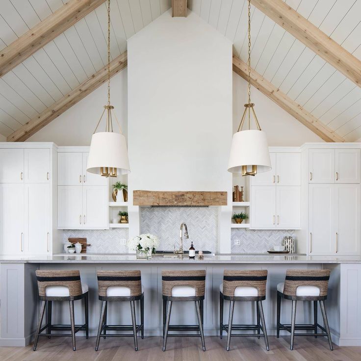 a large kitchen with white cabinets and wooden beams on the ceiling, along with bar stools