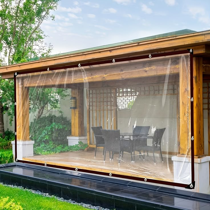 a covered patio with table and chairs in the back yard, surrounded by green grass