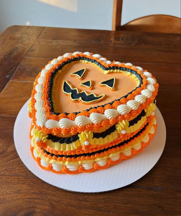 a heart shaped cake on top of a white plate with orange and black icing