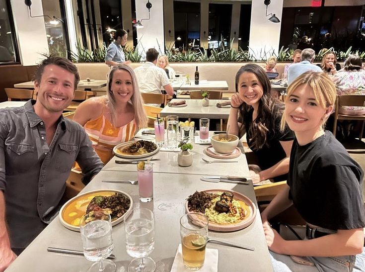 three people sitting at a table with plates of food