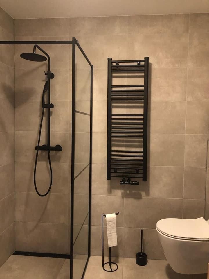 a bathroom with a toilet, shower and sink in it's corner area next to a wall mounted radiator