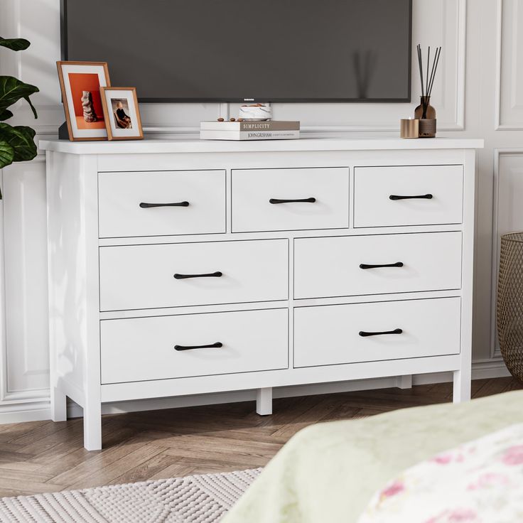 a flat screen tv sitting on top of a white dresser