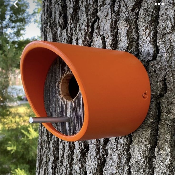 an orange bird house attached to a tree