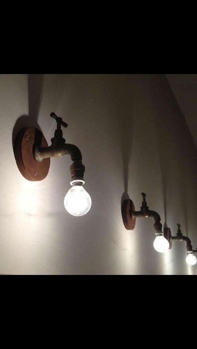 three light bulbs are on the wall next to some pipes and faucet lights