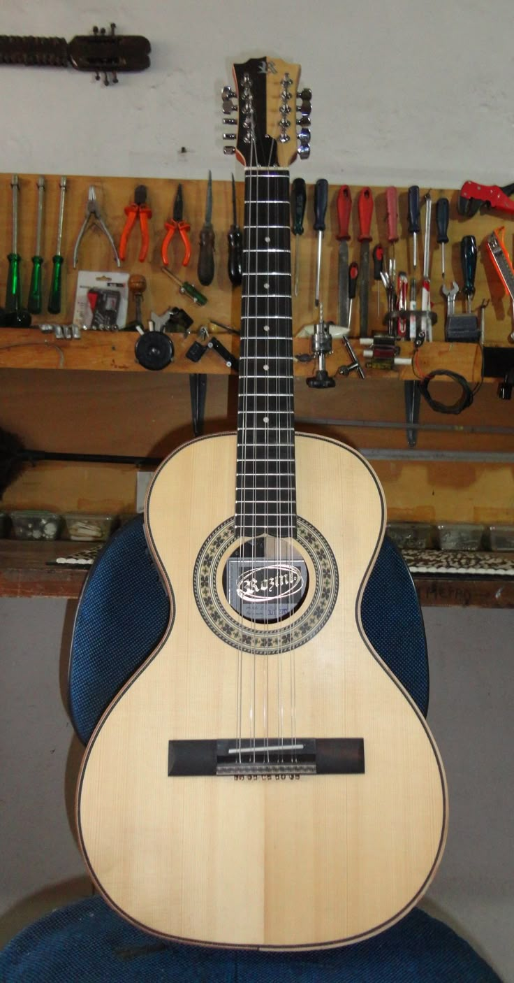 a guitar sitting on top of a blue chair in front of a workbench