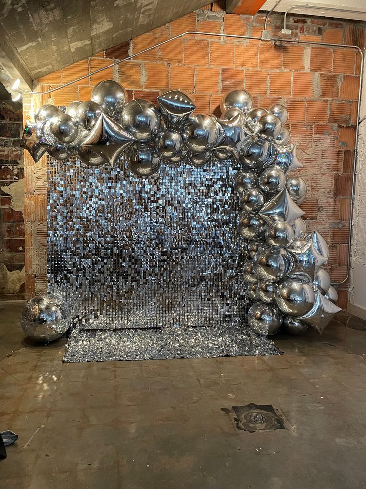 an art installation made out of metal balls and mirrors in a room with exposed brick walls