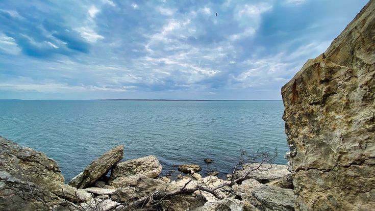 some rocks and water under a cloudy blue sky