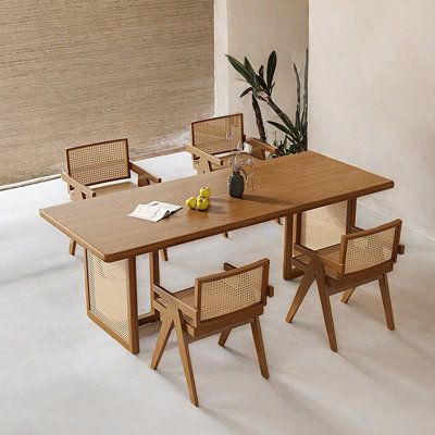 a wooden table with chairs around it and a plant in the corner next to it