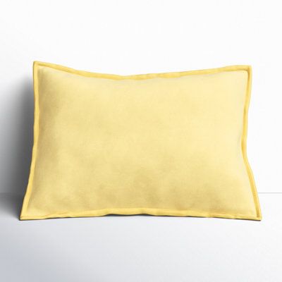 a yellow pillow sitting on top of a white wall