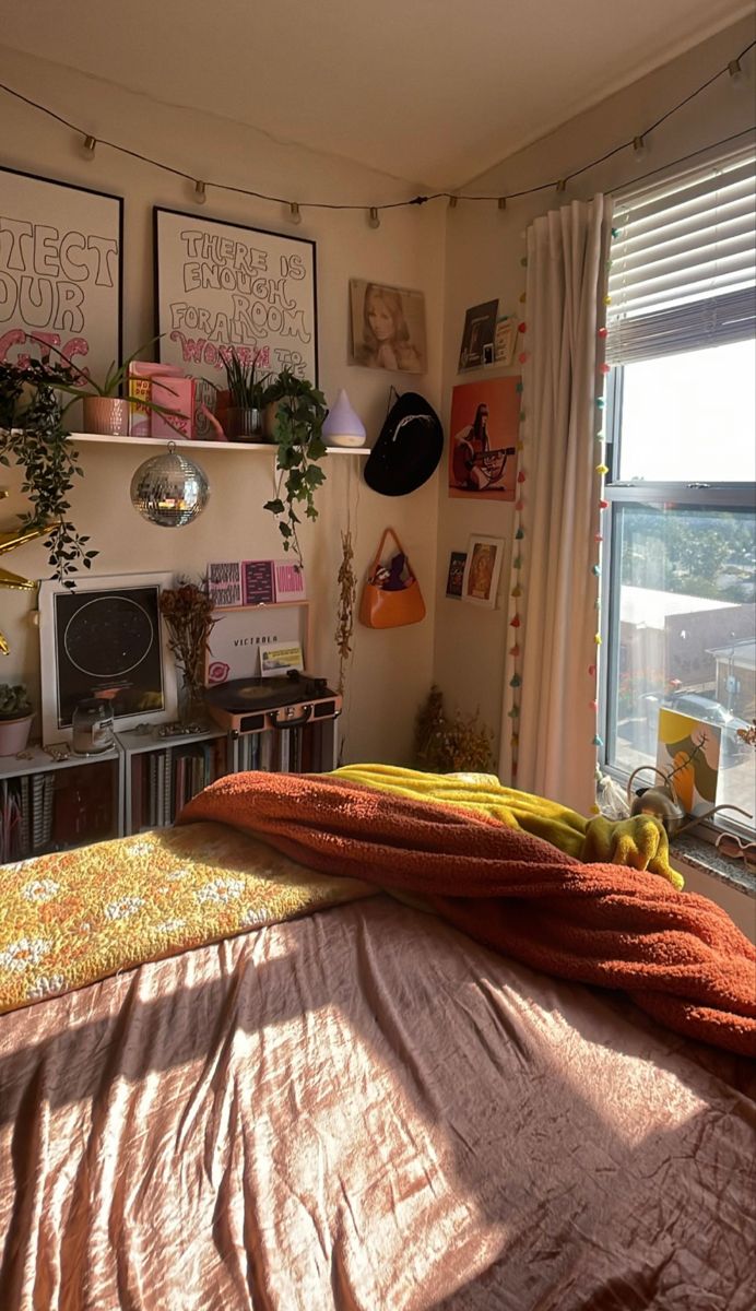 an unmade bed sitting next to a window in a room with pictures on the wall