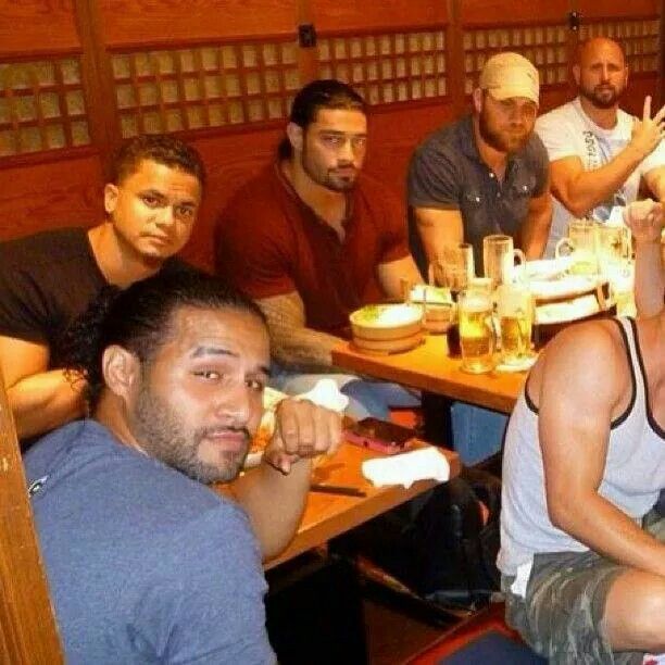 a group of men sitting at a table eating food and drinking beer in a restaurant