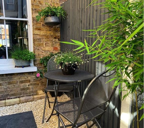 an outdoor table and chairs with potted plants