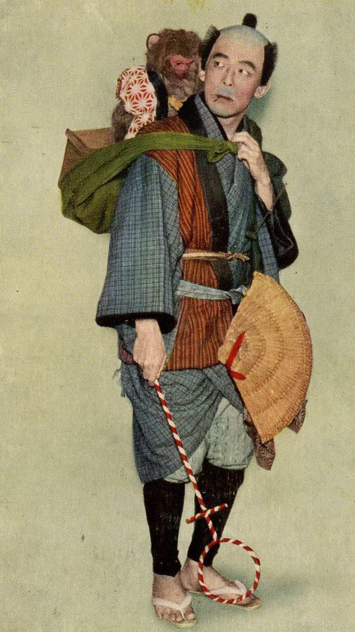 an old man in traditional japanese clothing holding a doll and candy cane, with a mouse on his shoulder