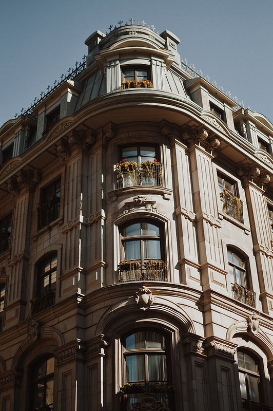 an ornate building with many windows and balconies on the top floor, against a blue sky