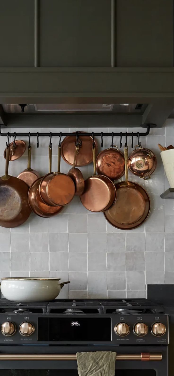 pots and pans are hanging on the wall above an oven