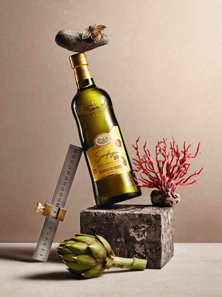 a bottle of wine sitting on top of a stone block next to a plant and a knife