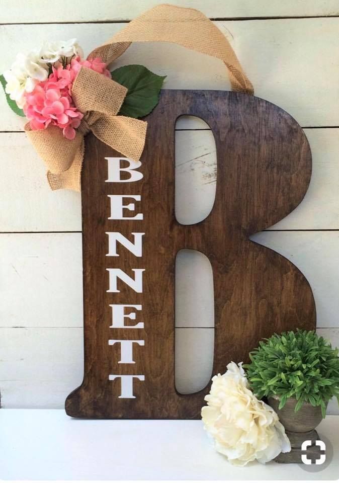 a wooden sign with the letter b on it and flowers in vases next to it