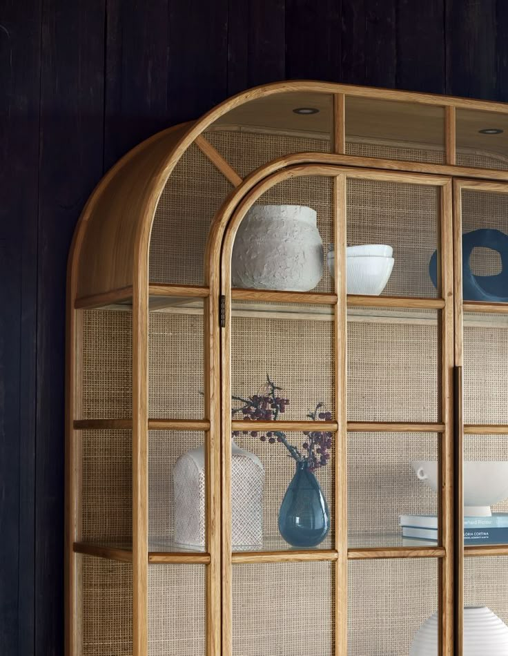 a wooden shelf with glass doors and vases