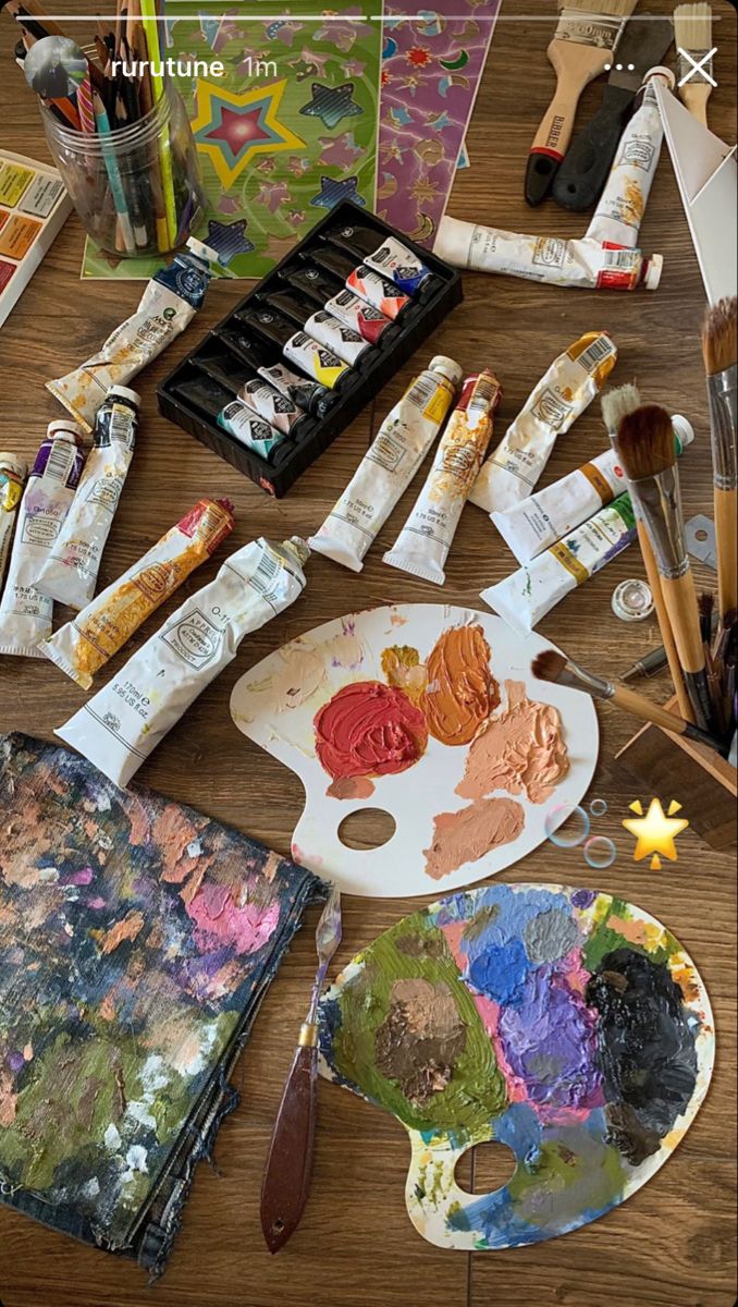 an assortment of art supplies including paint, brushes and palettes on a wooden table