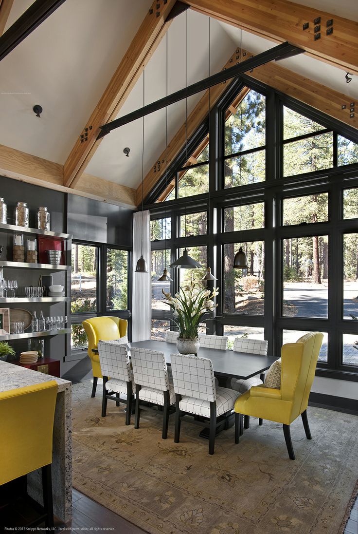 a dining room table with yellow chairs in front of large windows