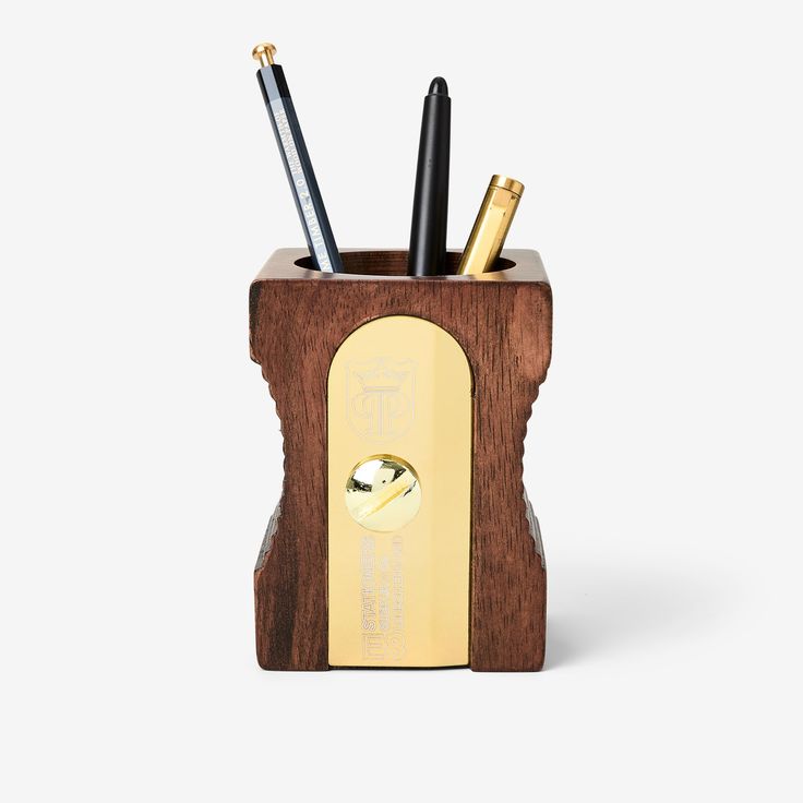 a wooden pen holder with three pens in it