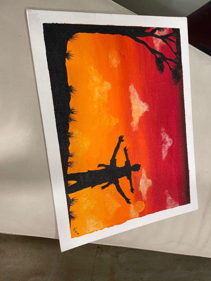 an art piece is hanging on the wall in front of a white canvas with orange and red colors