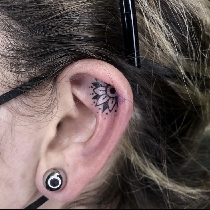 a woman with a black and white tattoo on her ear