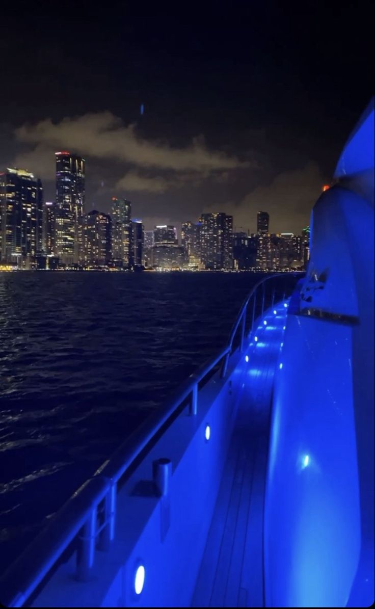 the city skyline is lit up at night as seen from a boat on the water