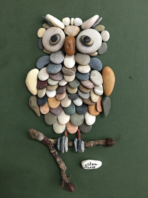 an owl made out of rocks sitting on top of a tree branch