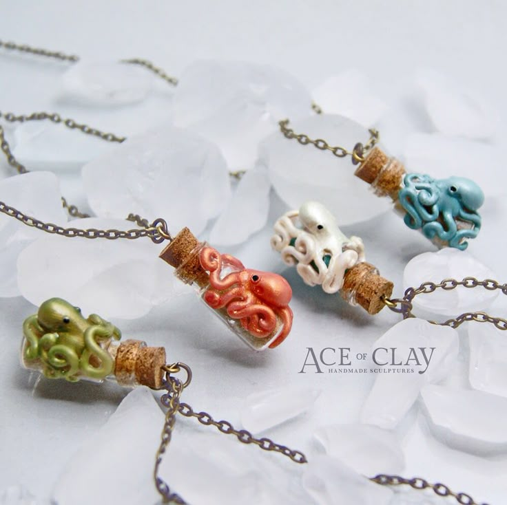 three necklaces with different designs on them sitting on some ice crystals and silver chains