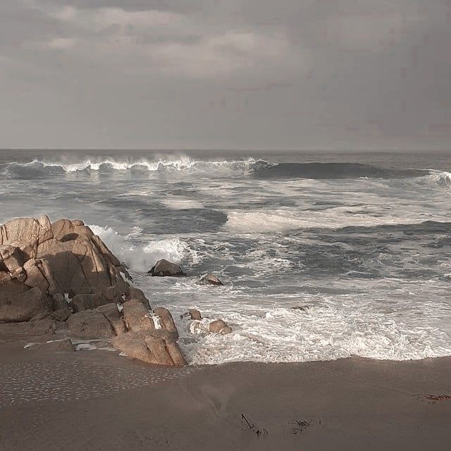 an ocean view with waves crashing on the rocks