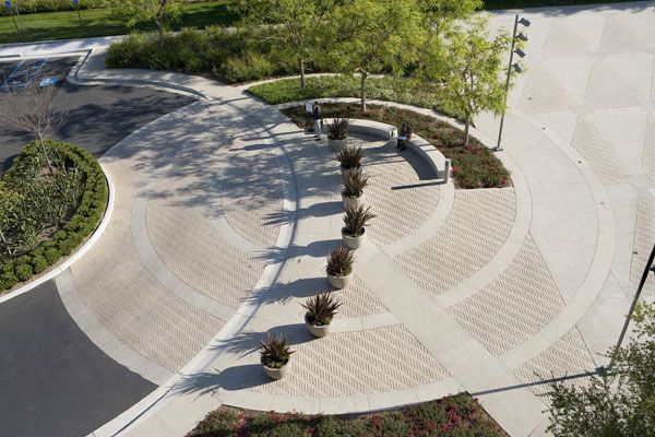 an aerial view of a circular park with trees and plants in the center, surrounded by concrete walkways